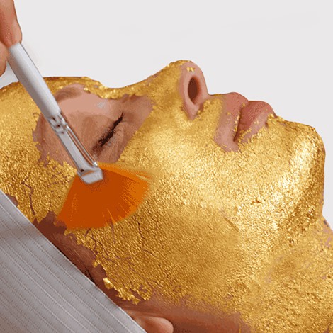 Woman's face being coated in a thin layer of gold